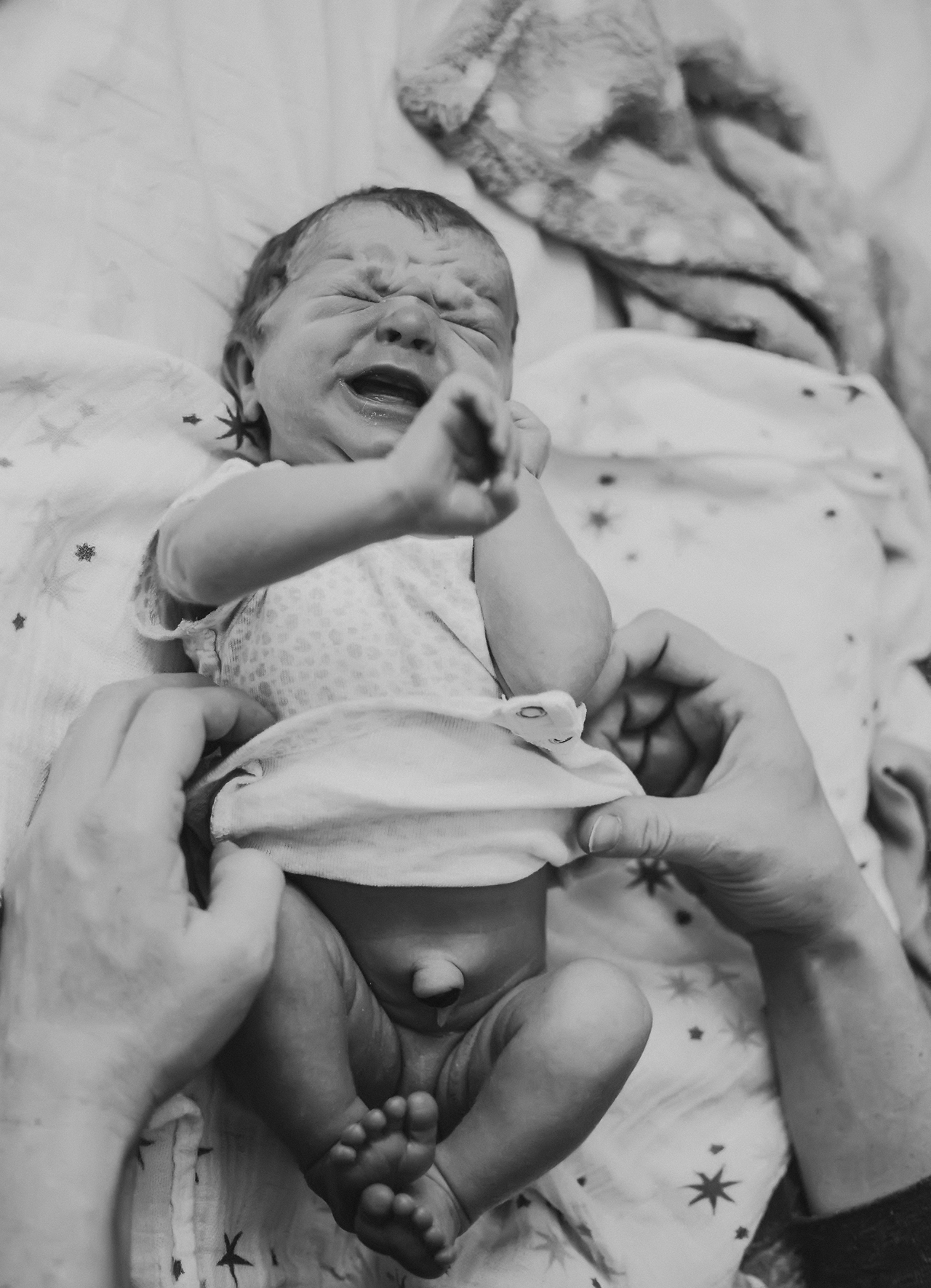 Newborn baby cries as mother changes diaper, black and white photo by Natalie Broders Newborn baby cries as mother changes diaper, black and white photo by Natalie Broders