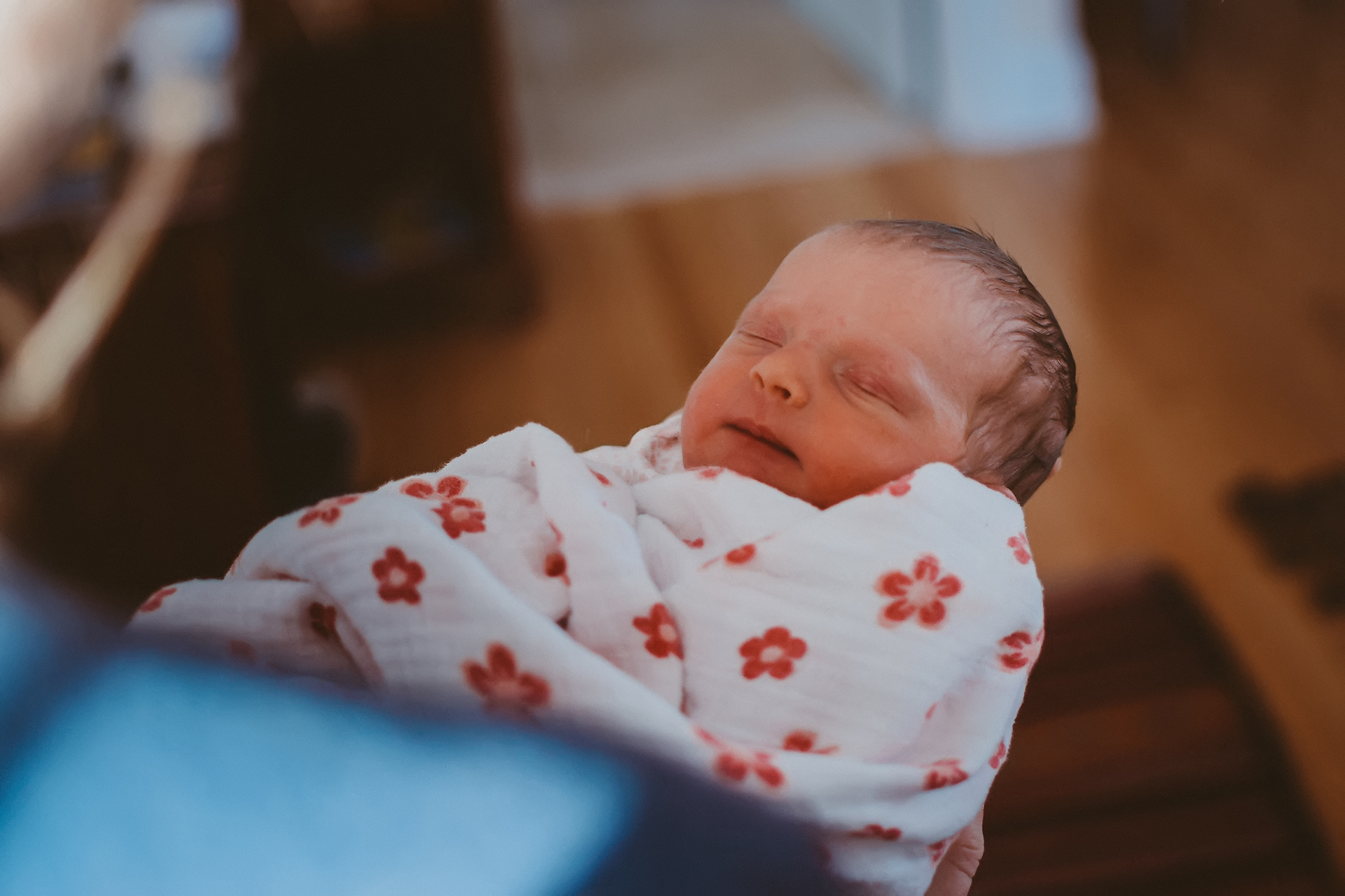 Looking over mother's shoulder at newborn baby all swaddled up Looking over mother's shoulder at newborn baby all swaddled up
