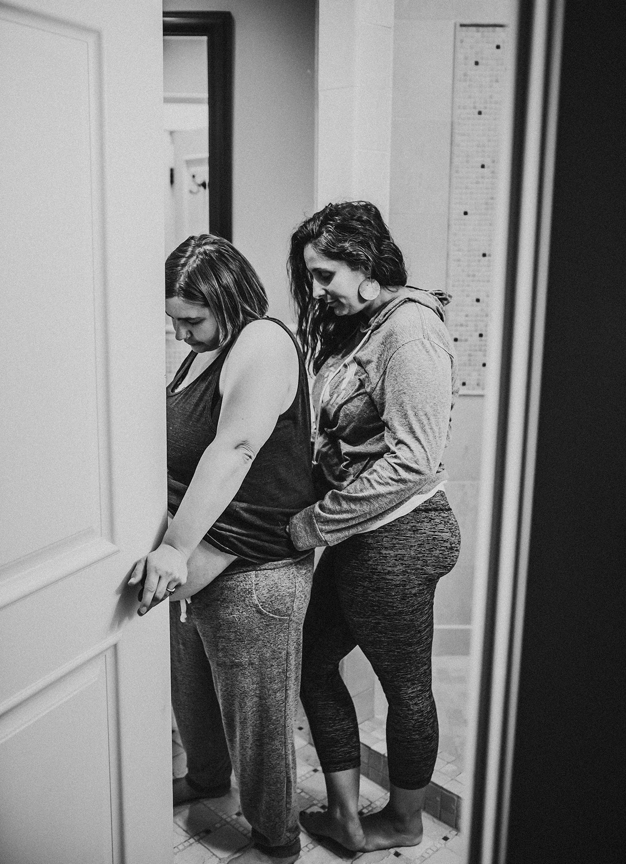 Woman laboring in the bathroom is supported by her doula Woman laboring in the bathroom is supported by her doula
