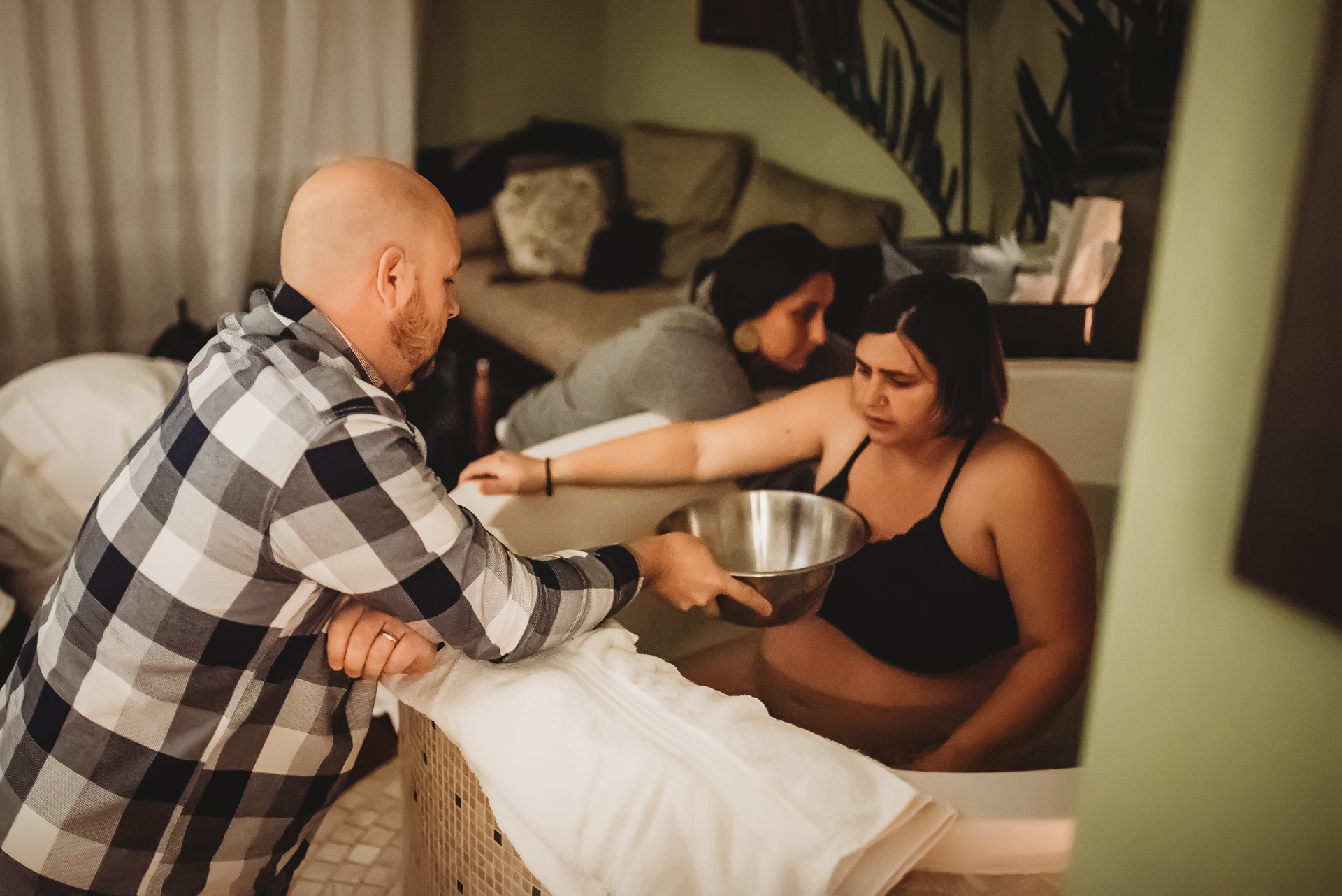 Birth partner husband holds a bowl for a woman in labor in case she vomits Birth partner husband holds a bowl for a woman in labor in case she vomits
