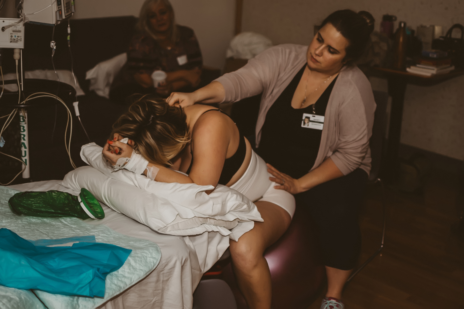 Laboring woman sitting on a birthing ball being massaged by her doula Laboring woman sitting on a birthing ball being massaged by her doula