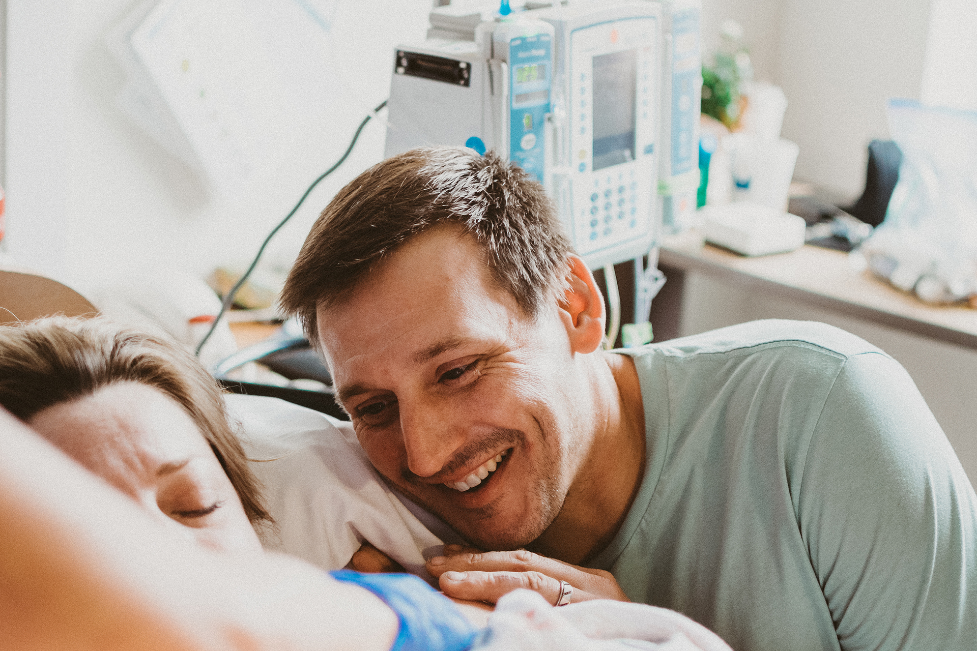 New father smiles down at his newborn baby girl on mother's chest immediately after birth New father smiles down at his newborn baby girl on mother's chest immediately after birth