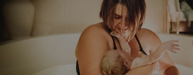 Mother is overcome with emotion looking down at her baby born in a birthing tub at Andaluz Waterbirth Center Mother is overcome with emotion looking down at her baby born in a birthing tub at Andaluz Waterbirth Center